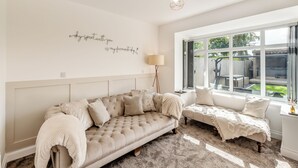 Een gezellige kamer met een groot raam, een bank, een leeshoek en een decoratief wandobject.