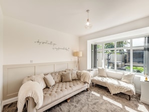 Une pièce confortable avec une grande fenêtre, un canapé, un fauteuil de lecture et un élément décoratif mural.