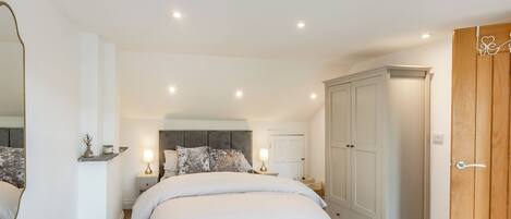 A bedroom with a bed, bedside tables, a wardrobe, and a mirror.