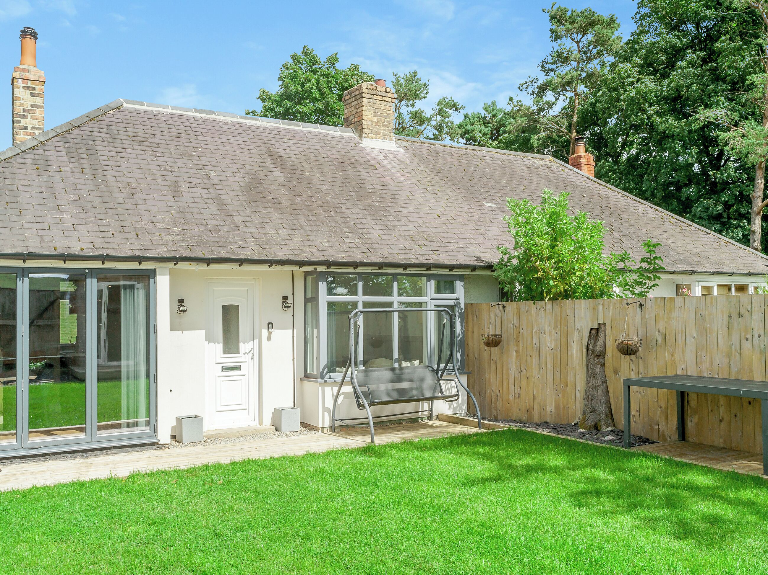 A house with a brick roof, a wooden fence, and a grassy yard.