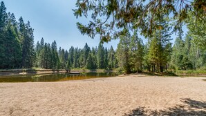 Une plage de sable bordée d’un lac paisible, le tout entouré d’une forêt dense.