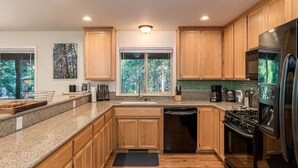 Una cocina con armarios de madera, encimeras de granito, lavavajillas, estufa y refrigerador.