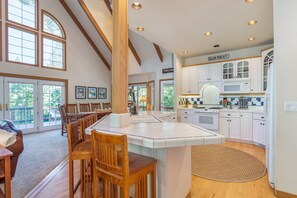 Una cocina amplia con alacenas blancas, una isla central y un comedor con sillas de madera.