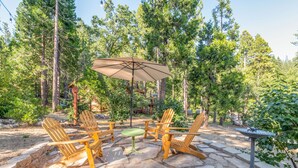 An outdoor patio with stone flooring, wooden Adirondack chairs, a table, and a large umbrella. - Bear House - Walking Distance to Snowflake Lodge, Pool,Lake and Recreation! (Arnold)