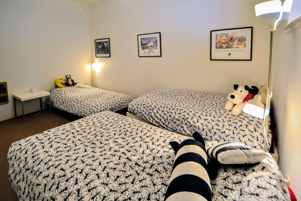 A room with two beds, a nightstand, and three framed pictures on the wall.