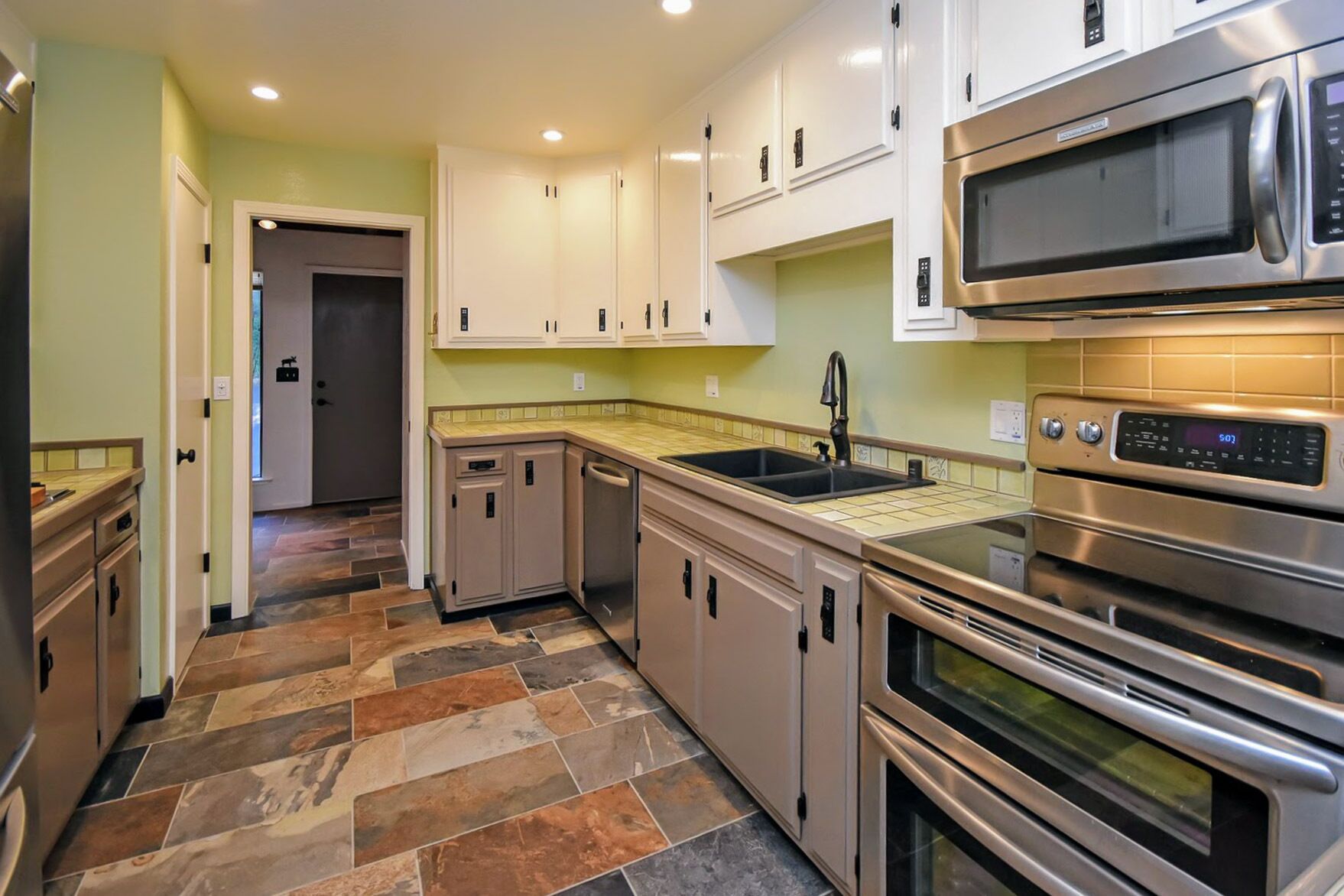 Eine moderne Küche mit Edelstahlgeräten, einer Fliesenrückwand und verschiedenen Schränken.