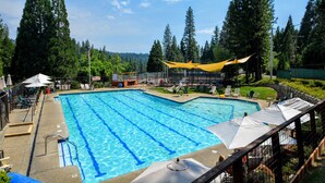 A swimming pool with clear blue water, surrounded by trees and shaded by yellow canopies. - HUGGING TREES - 4 BEDROOM 2 full, 2 half  BATH WITH GAME ROOM, SLEEPS 12 (Arnold)