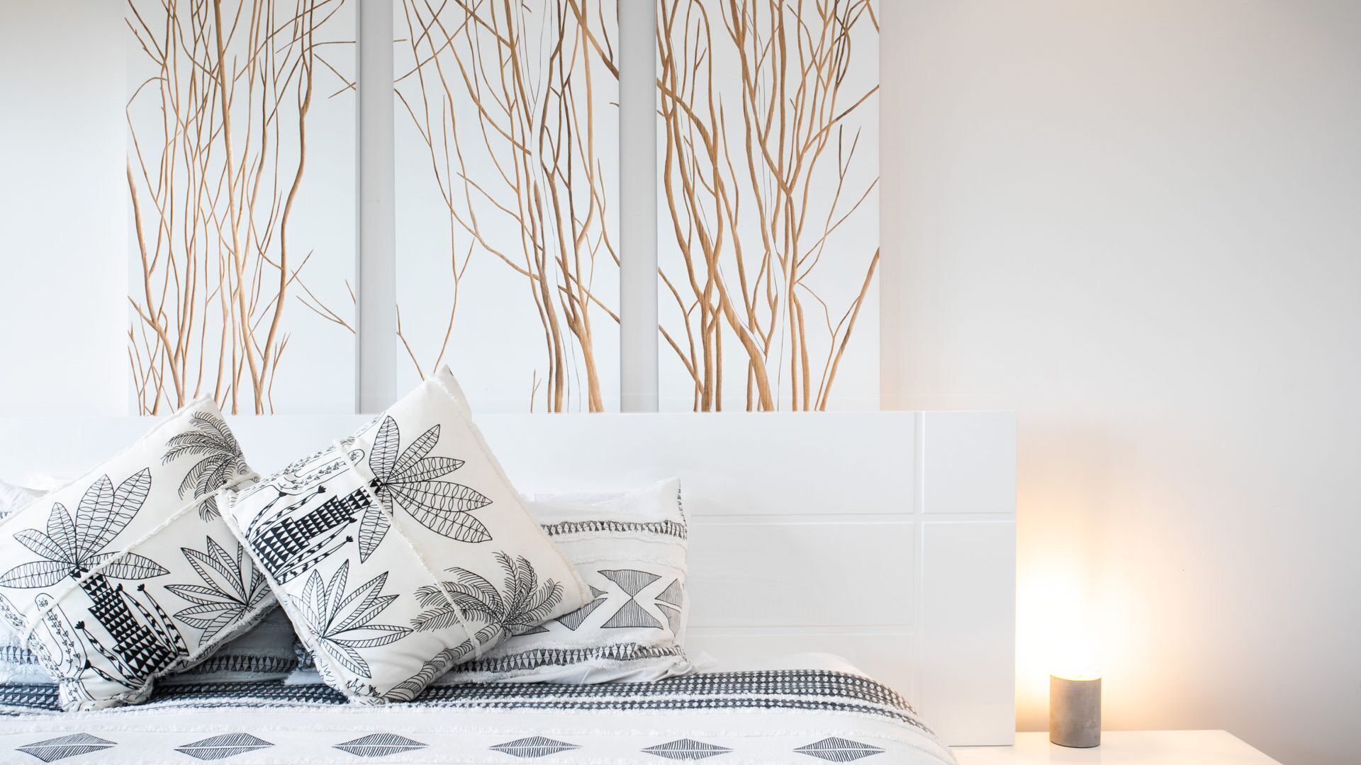 Ein Schlafzimmer mit Bett, Kissen, einem Nachttisch und einer Wand mit vertikalen Linien.