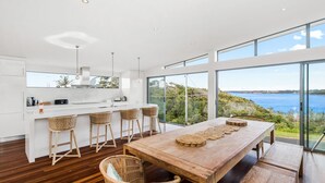 A modern kitchen with a large island, bar stools, and a view of the sea.