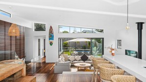A modern living room with a pool view, wooden flooring, and wicker furniture.