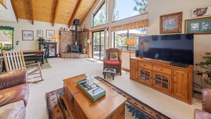 Un salon chaleureux avec une cheminée en pierre, des meubles en bois et un grand téléviseur.