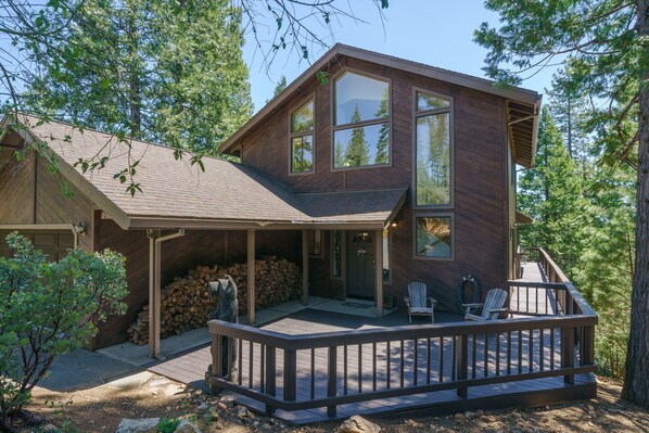 A two-story wooden house with a covered porch and a deck.