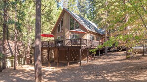 A cabin with a deck, surrounded by trees. - Pop's Place - Air Conditioned Cabin w/ Access to Golf and BLS (Arnold)