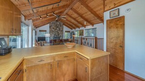 A spacious kitchen with wooden cabinets, a stone accent wall, and a ceiling fan.