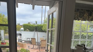 A room with a sliding glass door leading to a patio area with a brick floor and outdoor furniture. - Beach, bay, town, walking distance.  Large private fenced in home (Coronado)