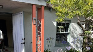 A garden with a brick pathway leading to a door, surrounded by various plants and flowers. - Beach, bay, town, walking distance.  Large private fenced in home (Coronado)