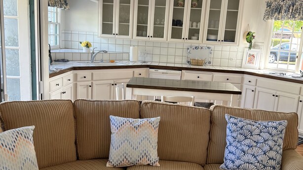A modern kitchen with white cabinetry, a central island, and a dining area. - Beach, bay, town, walking distance.  Large private fenced in home (Coronado)
