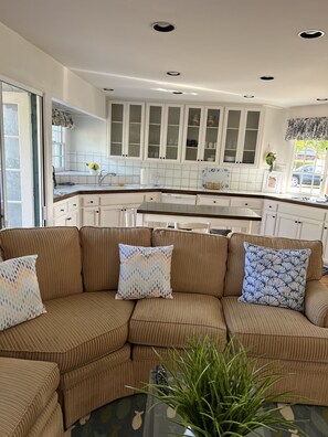A modern kitchen with white cabinetry, a central island, and a dining area. - Beach, bay, town, walking distance.  Large private fenced in home (Coronado)