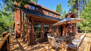 Een houten chalet met terras, buitenmeubels en grote ramen.
