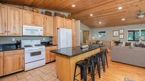 A spacious kitchen with wooden cabinets, a central island with bar stools, a microwave, a refrigerator, and a stove. - WALK TO LAKEMONT PINES LAKE AND ARNOLD RIM TRAIL W/AIR CONDITIONING (Arnold)