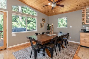 A dining room with a wooden table, six chairs, two candles, and a ceiling fan.