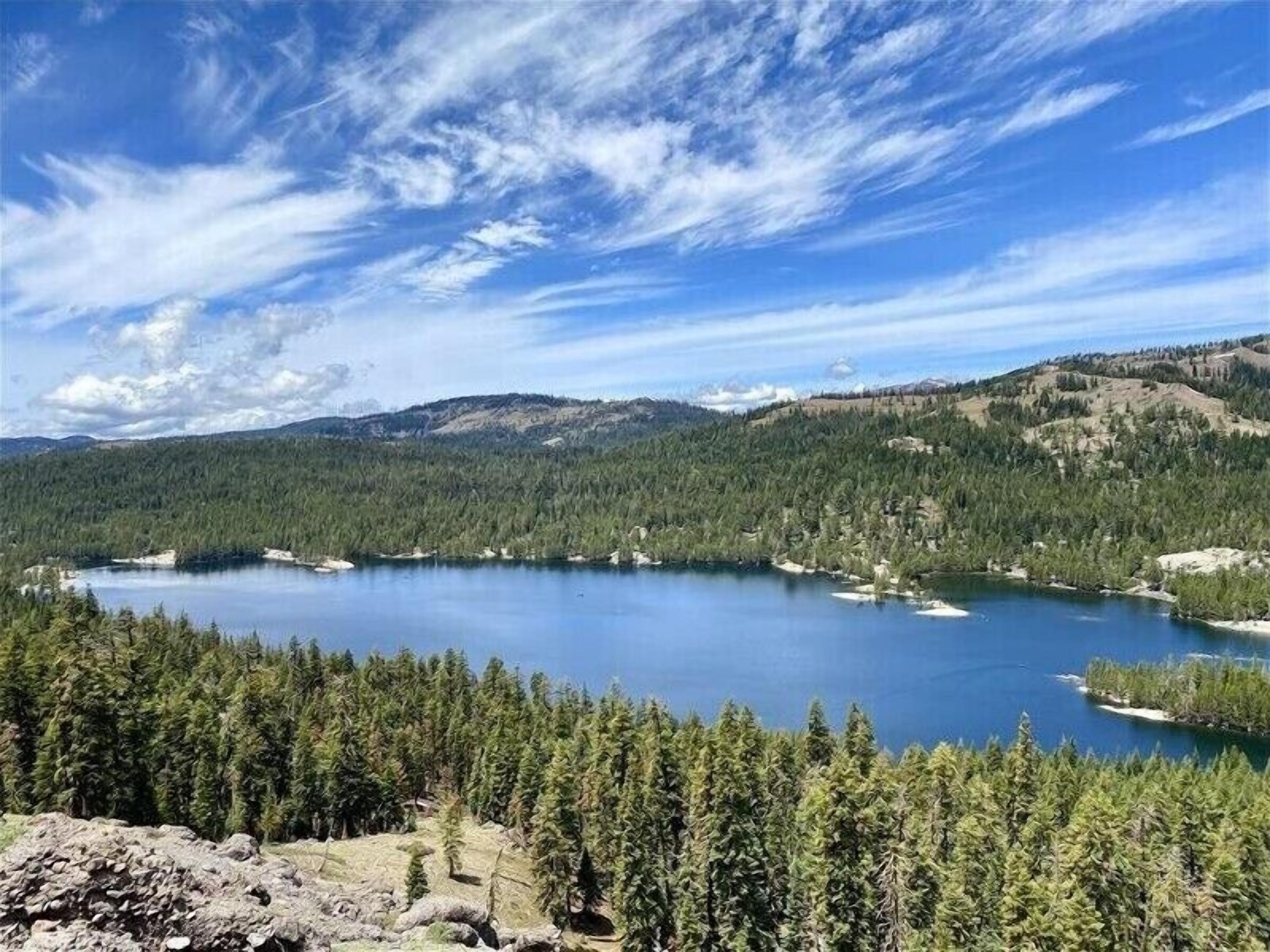 A lake surrounded by dense forest and mountains under a clear sky.