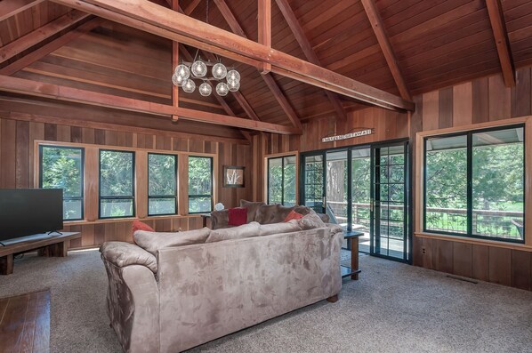 Relax in this inviting living area with a plush sofa, large windows, and a high ceiling.