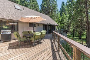 A deck with outdoor furniture, a grill, and a large umbrella.