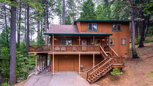 Une cabane en rondins à deux étages, dotée d’un porche à l’avant, d’une terrasse couverte et d’un escalier menant à l’étage supérieur.