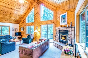 A cozy cabin interior with a fireplace, large windows, and a comfortable seating area. - Sunset View- ACCESS TO GOLF + SNOWFLAKE LODGE (Arnold)