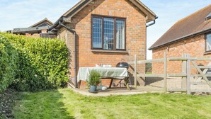A brick house with a pitched roof, a window, and a small table with a kettle and teapot.