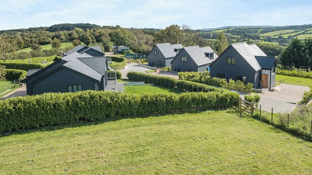 A residential area with modern houses, a well-maintained lawn, and a clear view of the surrounding countryside.