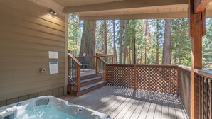 Ein Whirlpool auf einer Holzterrasse mit Blick auf hohe Bäume.