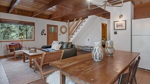 Un accogliente soggiorno con un tavolo da pranzo in legno, un divano e una scala che conduce a un altro livello.