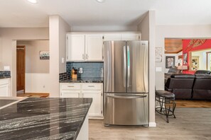 A modern kitchen with white cabinets, a stainless steel refrigerator, and a marble countertop. - OUR SILVER LINING- W/REC ROOM + AC + WHOLE HOUSE GENERATOR (Arnold)