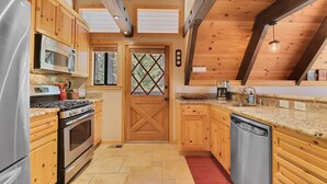Une cuisine avec des meubles en bois, un réfrigérateur en acier inoxydable, une cuisinière et un lave-vaisselle.