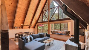 Un salon chaleureux de style loft, avec un grand plafond en bois, un canapé, une table basse et une cheminée.