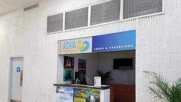 Un comptoir d’accueil avec une enseigne indiquant « AQUA TERRA TOURS & EXCURSIONS » et une affiche faisant la promotion d’une cascade.