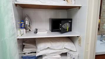 Habitación de hotel con cama, microondas, secador de pelo y artículos de aseo en los estantes.