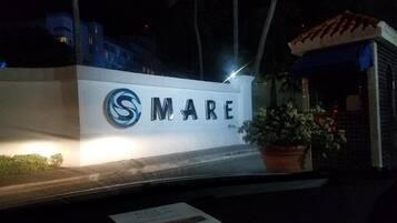 Un letrero con la palabra "SMARE" iluminada de noche, que indica el nombre de un hotel o propiedad.