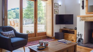 A living room with a large window, a television, a fireplace, and a cozy seating area.