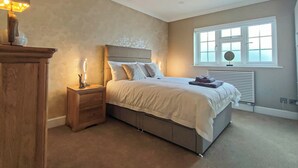 Ein Schlafzimmer mit Bett, Nachttisch, Kommode und einem Fenster mit Jalousien.