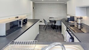 Eine kompakte Küche mit modernem Design, ausgestattet mit einem Backofen, einer Kaffeemaschine und einem Spülbecken.