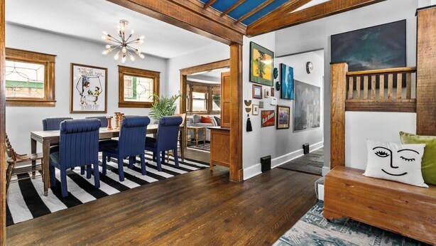 A dining area with a wooden table and blue upholstered chairs, a chandelier, and artwork on the walls. - Spacious Home in KC's Core 46 (Kansas City)