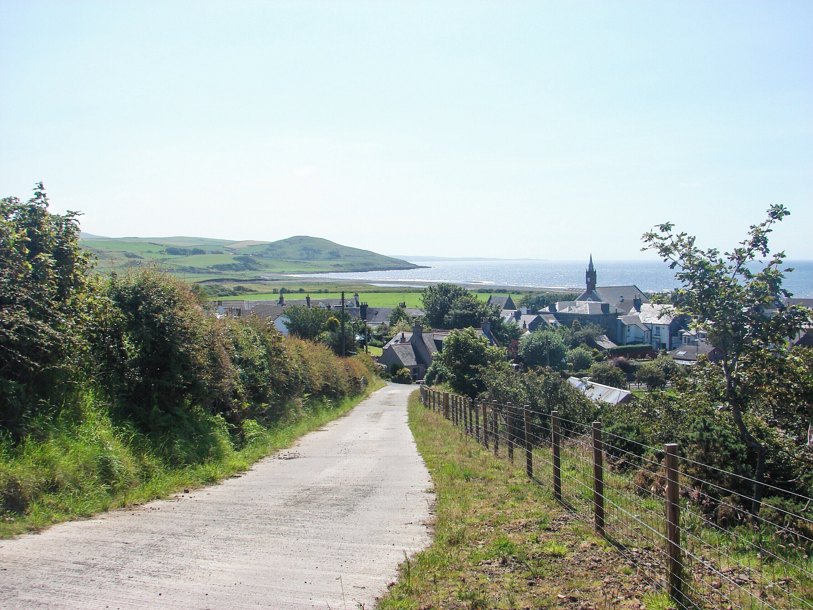 En landevej der fører til en landsby med huse og en kirke.