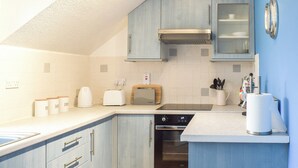 A kitchen with light blue cabinets, a built-in oven, a toaster, and a coffee maker. - A perfect coastal escape for couples and friends. (Ballantrae)