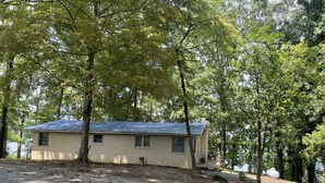 A single-story house with a sloped roof, surrounded by trees. - Weiss Lake Rustic Cabin on the water, new flooring! (Centre)