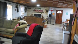 A cozy living room with a sofa, armchair, wooden ceiling, and a fireplace. - Weiss Lake Rustic Cabin on the water, new flooring! (Centre)