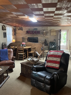 A cozy living room with a fireplace, a dining area, and a black leather armchair.
