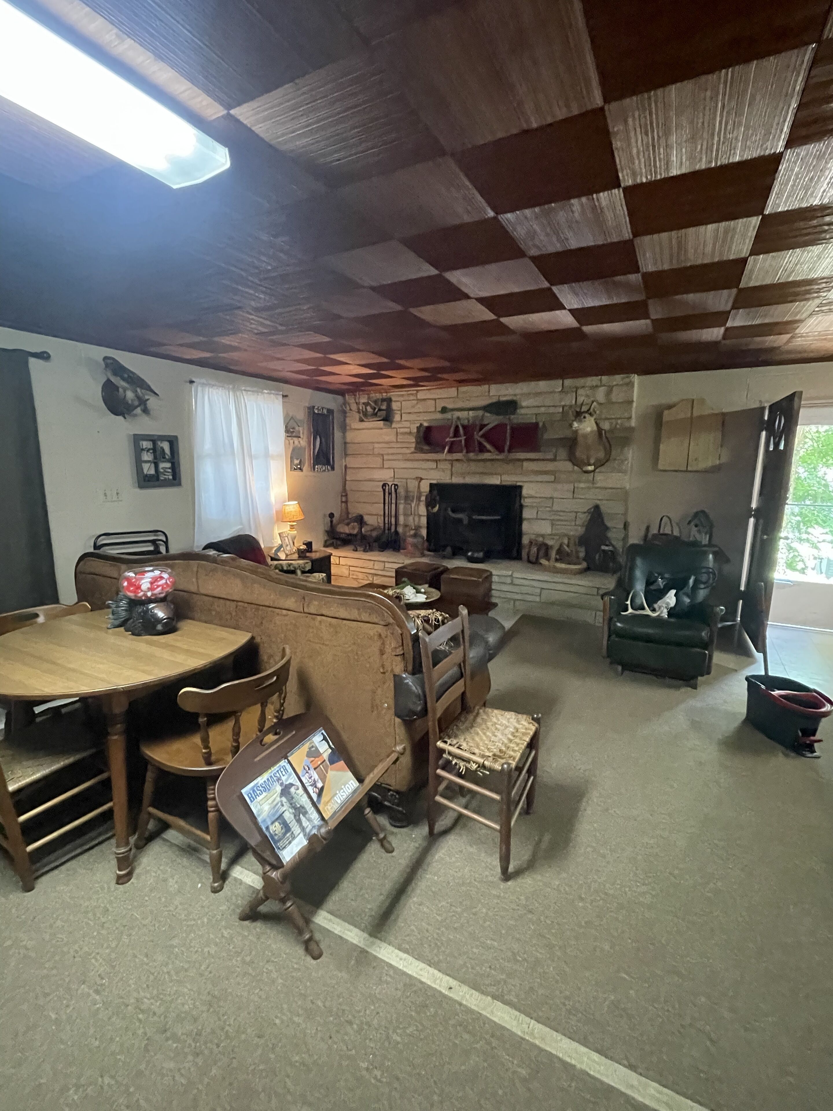 Ein gemütliches Wohnzimmer mit karierter Decke, Kamin und Essbereich mit Holzmöbeln.